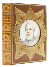 Load image into Gallery viewer, Oblique view of the front cover and spine of the brown morocco Cosway binding featuring a central circular portrait miniature of Robert Browning under glass with radiating gilt lines